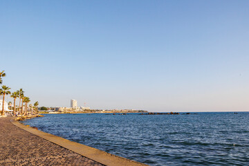 View of the coastline with palm trees along the promenade in Paphos, Cyprus, clear blue sky, 23.11.2024