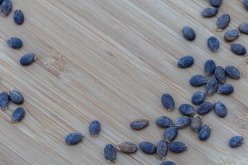 Dark blue seeds of watermelon on wooden background with copy space, sowing concept