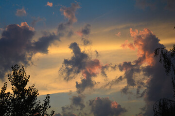 A stunning sunset sky with dramatic clouds illuminated by golden and pink hues. The contrast...