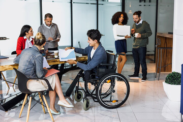 latin business teamwork and young man in wheelchair working at office in Mexico Latin America,...