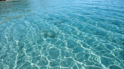 Crystal-clear blue water with sunlit ripples forming mesmerizing reflections. A tranquil aquatic background perfect for summer, relaxation, and peaceful scenery