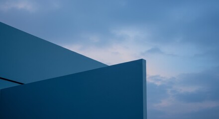 A minimalist architectural structure with a smooth, curved blue concrete surface against a cloudy gradient blue sky, emphasizing geometric shapes and clean lines.

