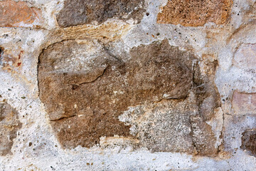Weathered stone wall with peeling plaster
