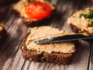Rustic Pate, man smear on Black Bread with Fresh Herbs and tomatoes