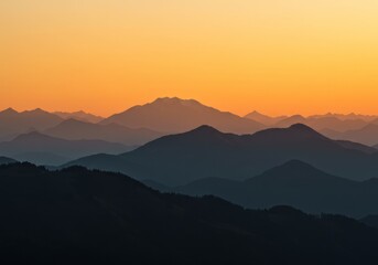 Photograph of a serene mountain landscape at sunset, with silhouetted mountains and a gradient sky of orange to yellow, creating a calm and peaceful atmosphere.

