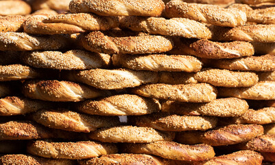 Heap of simit, a traditional Turkish sesame-covered round bread with a crispy crust and soft interior, commonly enjoyed with breakfast items and tea, and sold by street vendors and bakeries