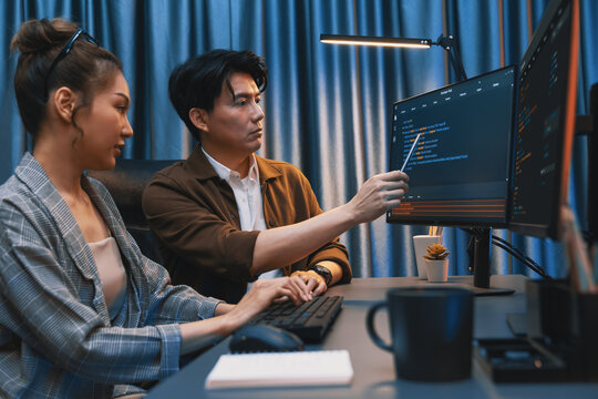 IT developers discussing with point to intelligent website development coder system running data online two screens information technology at neon light room at modern office. Infobahn.