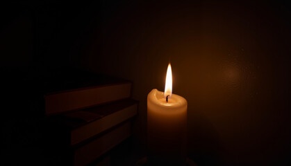 Candle flame illuminating books against a dark background