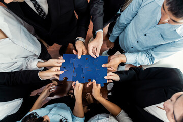 Top view multiethnic business people holding jigsaw pieces and merge them together as effective...