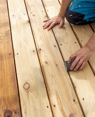 Man is sanding a wooden floor with a sanding block