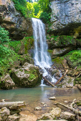 Obraz premium a waterfall, a fragment of a mountain river in the embrace of a stone canyon and a deep riverbed, a spring day in nature