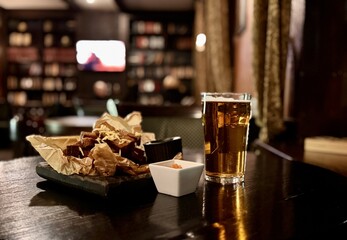 Enjoying delicious fried snacks accompanied by flavorful dips and a refreshing cold beer in an inviting cozy setting