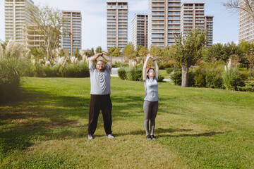 Fototapeta premium Man with extra weight and woman coach doing warm up in the park before jogging