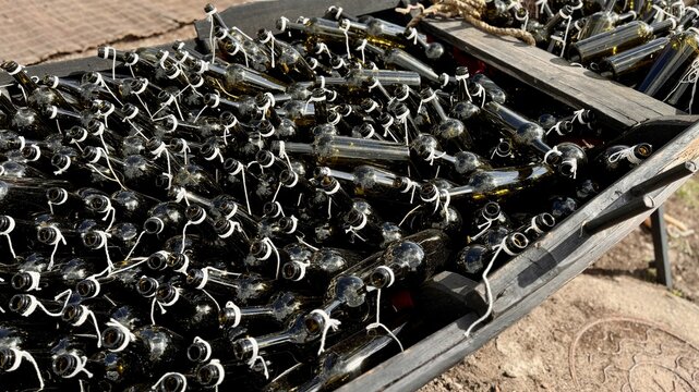 Empty dark wine bottles in close-up at an exhibition and sale of high-quality alcohol. A large number of bottles in the form of silhouettes and shapes in the design with garters and bows