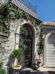 Ornate wrought iron gate set within a stone archway, covered with climbing ivy