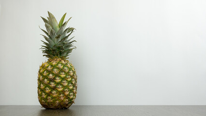 One pineapple on the left on the desk on white background