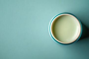 A cup filled with milk sits on a bright blue surface