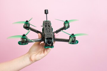 Hand holding modern drone with camera isolated on pink background