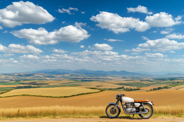 A beautifully restored vintage motorcycle parked on a dirt road overlooking a breathtaking countryside landscape.