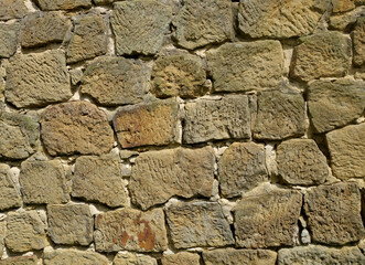The image is a close-up of a stone wall. The wall is made up of small, irregularly shaped blocks of different sizes and colors. The blocks are arranged in a grid-like pattern.