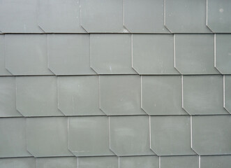 The image shows a close-up of a wall made up of gray tiles. The tiles are arranged in a grid-like...