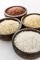 different kinds of asian rice grains in bowls on white background