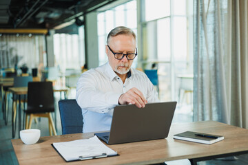 Fototapeta premium A businessman works diligently on his laptop in a modern office with a creative atmosphere