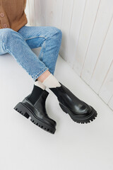 Female legs in jeans and black leather boots. Women's winter shoes