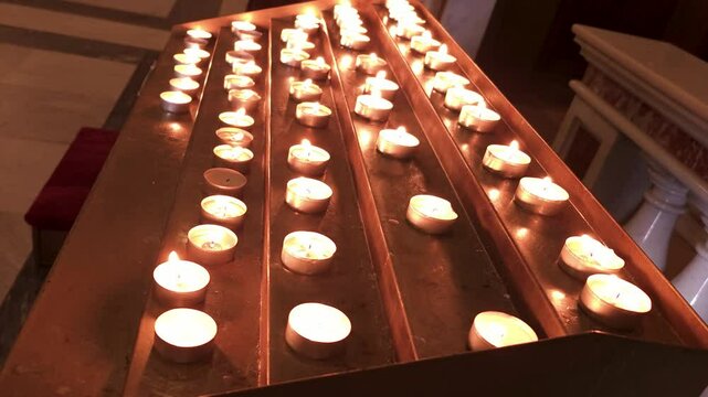 Rows of flickering prayer candles in a darkened cathedral
