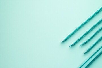 Obraz premium Four light teal colored pencils arranged diagonally on a light teal background.