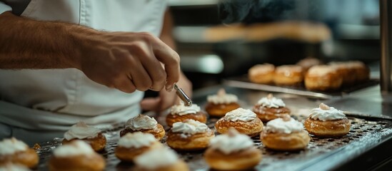 Baker carefully decorates freshly baked pastries with creamy topping in a professional kitchen.