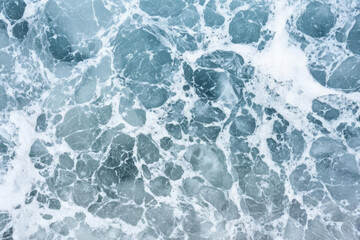 Ocean waves with foam creating textured pattern in blue tones