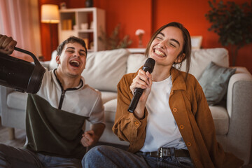 young couple girlfriend and boyfriend sit on floor and sing karaoke