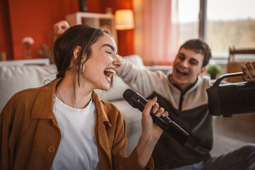 young couple girlfriend and boyfriend sit on floor and sing karaoke