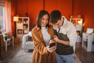 youth couple boyfriend and girlfriend use mobile phone for fun at home