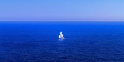 Obraz premium Solitary sailboat on a vast, blue ocean under a clear sky.