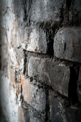 Close-up of a weathered, dark brick wall with textured mortar and faded paint.