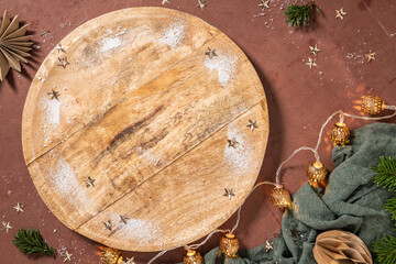 A cozy holiday setting with powdered sugar and star decorations on a wooden board, surrounded by festive lights and greenery. Top view