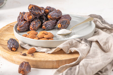 Medjool dates and almonds on a wooden tray with a spoonful of sugar, showcasing a healthy snack option