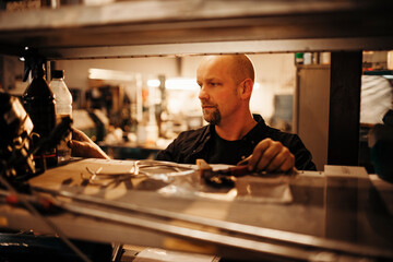 Middle aged caucasian man mechanic sorting his tools while working in a mechanics shop
