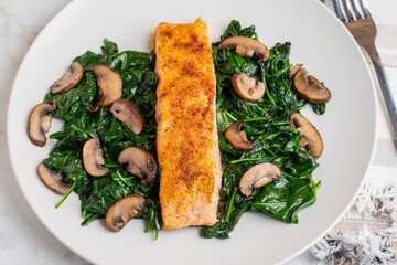 seasoned salmon resting on  spinach and mushrooms