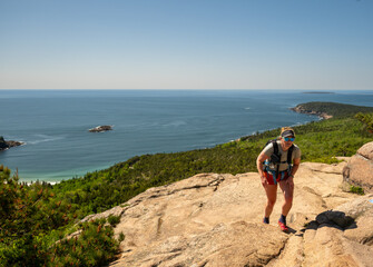 Woman Hikes Up Steep Rock Face Of The Beehive in Acadia