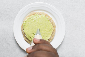 Overhead view of vanilla cookies being frosted, top view of cookies with buttercream frosting, process of frosting cookies