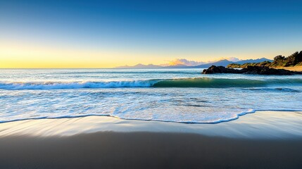 Obraz premium Gentle waves roll onto a sandy beach at sunrise