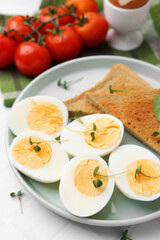 Cut hard boiled eggs with bread on white tiled table, closeup