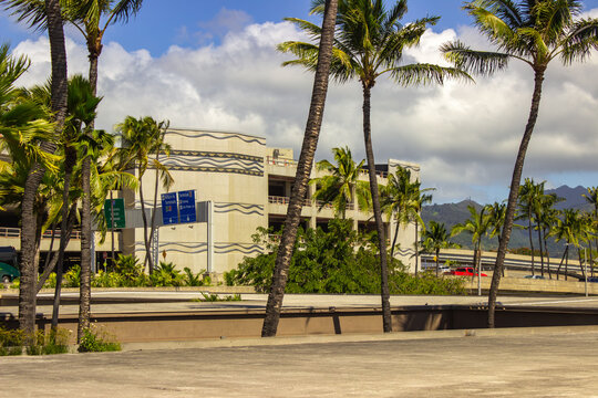 The Kona Airport in Hawaii, featuring a parking garage surrounded by lush palm trees under a bright blue sky, capturing the tropical essence of island travel.