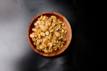 salted broad beans close-up in a wooden bowl. top view, good for recipe or commercial, isolated on black background