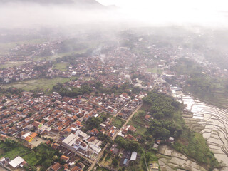 Aerial view of a residential neighborhood showcasing houses, roads, and trees on Foggy Morning. Fog covering residential District in the countryside. Drone Photography concepts. Negative Space