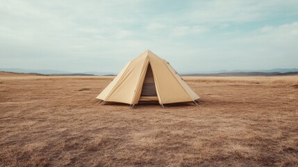 A solitary yellow tent stands in a vast dry landscape under a cloudy sky, evoking adventure