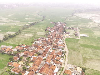 Cikancung, Indonesia. Aerial Landscape view of a remote village surrounded by rice field patches. High angle view of Residential District and agricultural fields. Panorama rural and suburban. Asia